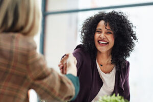 Smiling employee shakes hand with another employee.