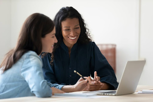 Two employees smiling at computer.